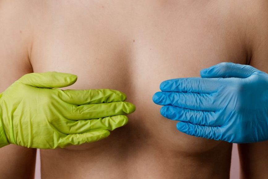 woman's breasts being covered by gloved hands