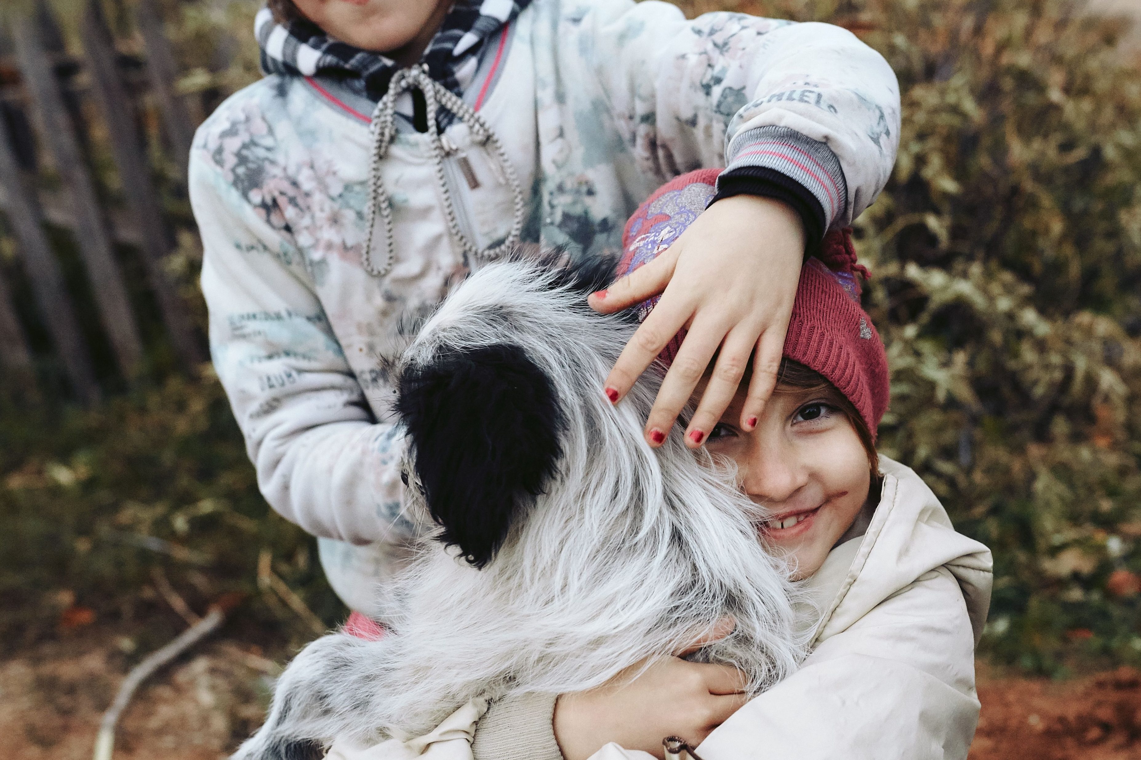 Two young kids hugging a dog.
